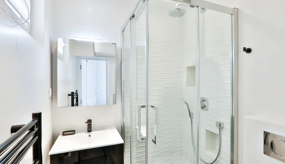 Bright, modern bathroom featuring a walk-in shower, designer vanity, and mirror. Sleek luxury for contemporary apartment living.