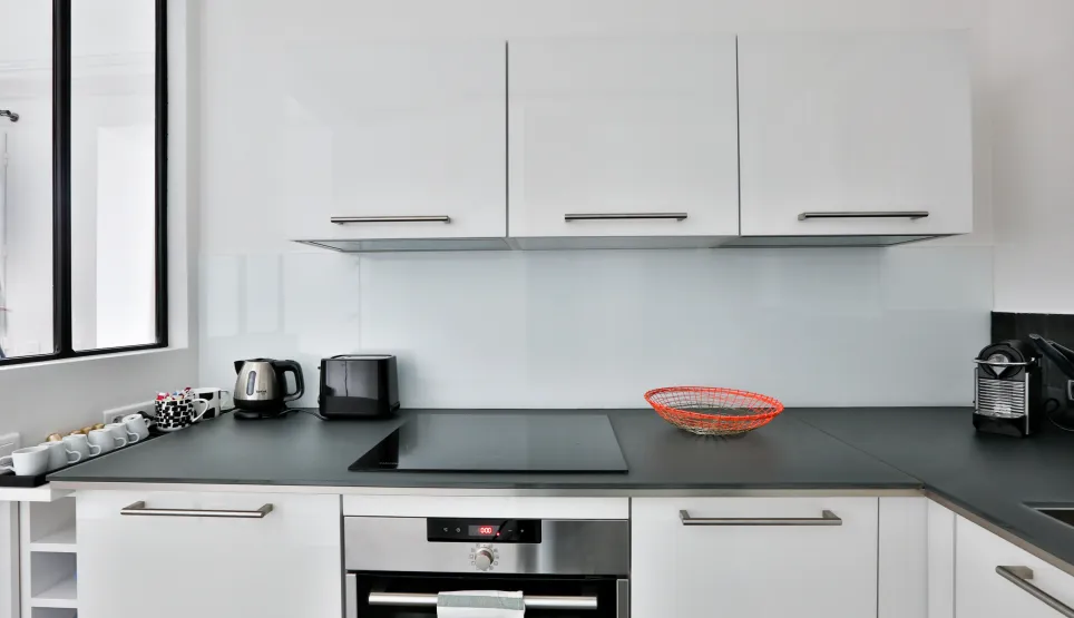 Sleek white modern kitchen with integrated appliances, dark countertop. Perfect for luxury apartment living.