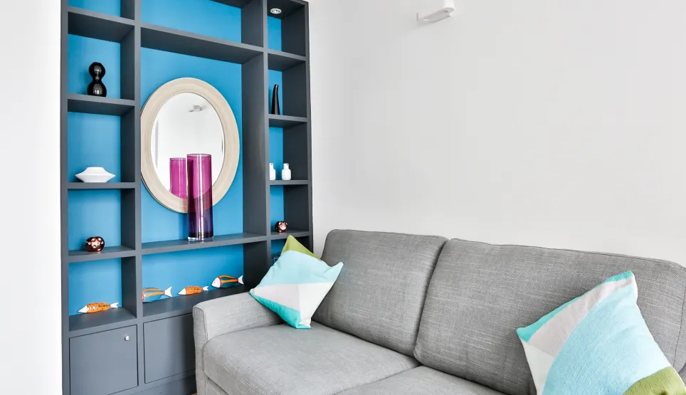 Bright modern living room with grey sofa, custom blue/grey shelving. Chic contemporary decor for a luxury home interior.