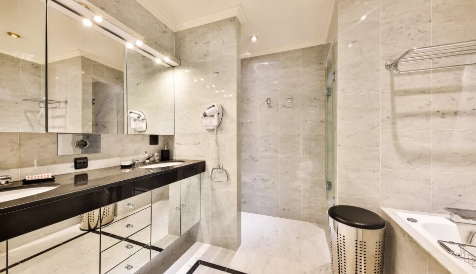 Luxury marble bathroom. Double vanity, illuminated mirror, shower, and bathtub. Modern and elegant design.
