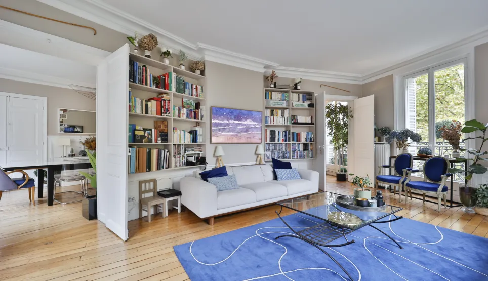 Luxury Parisian living room: bright, elegant apartment with hardwood floors, moldings, built-in bookshelves, and green views. Spacious design.