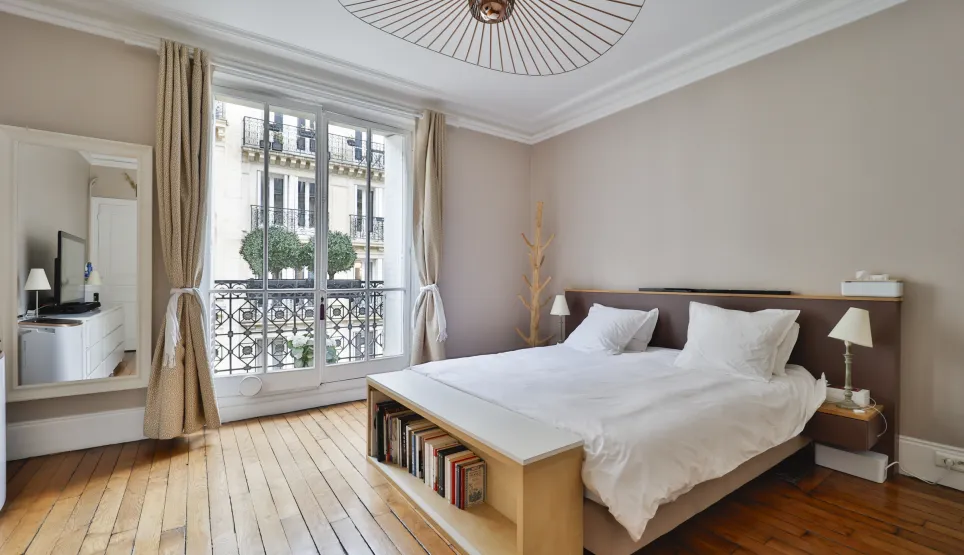 Luxury Parisian bedroom, hardwood floor, Haussmannian balcony view. Modern, minimalist design. Perfect for an exceptional property in Paris.