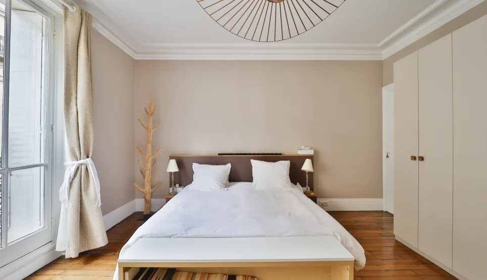 Bright luxury bedroom with hardwood floors, modern and sleek design. Ideal for an elegant and comfortable Parisian apartment.