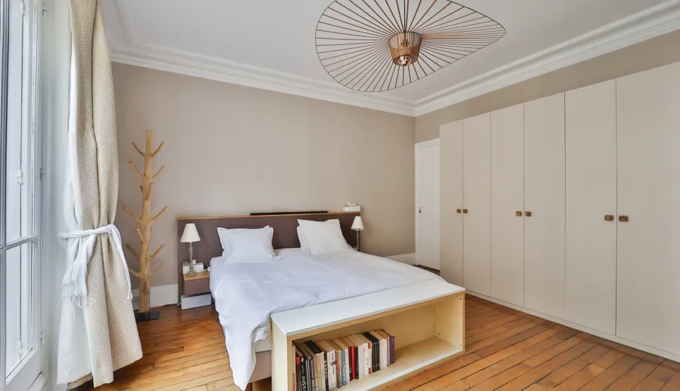 Modern luxury bedroom with comfortable bed, hardwood floors, built-in wardrobe, and designer lighting. Perfect for an elegant apartment.