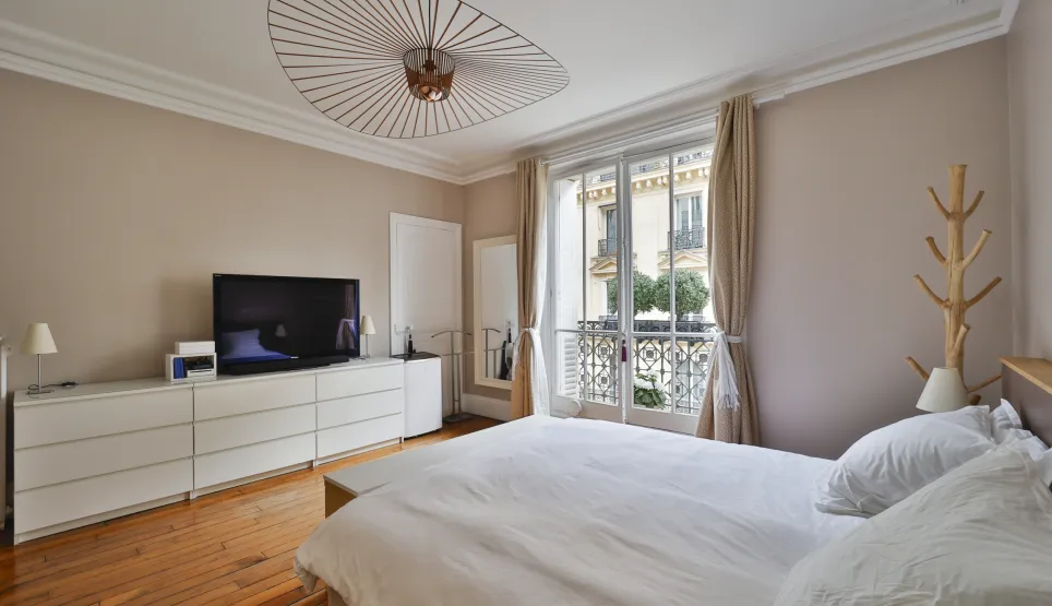 Modern luxury bedroom, balcony, hardwood floor, TV, designer lighting. Elegant and bright interior.