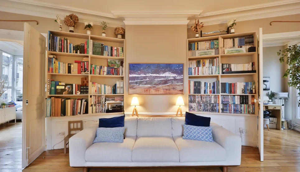Elegant luxury living room with built-in bookshelves, designer sofa, and art. Bright, refined ambiance, hardwood floors.