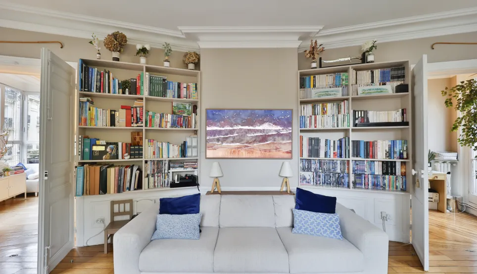 Elegant luxury living room: white sofa, built-in bookshelves, modern art. Refined ambiance for a high-end interior.