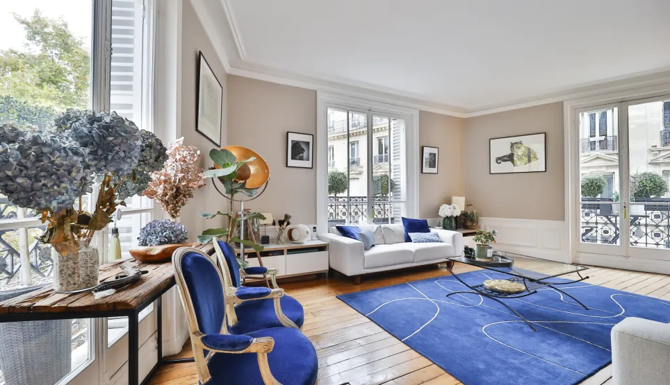 Luxury Parisian Haussmannian living room. Refined design, elegant blue furniture, parquet. Natural light, city view. Prestige apartment.