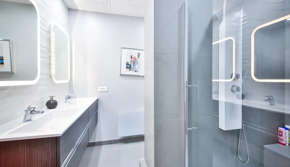 Modern luxury bathroom featuring double vanity, LED mirrors, and glass shower. Sleek design, high-end finishes for an exclusive property.