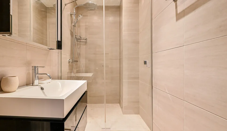 Contemporary bathroom: walk-in shower, designer sink, light tiles. Zen and luxury ambiance for exceptional property.
