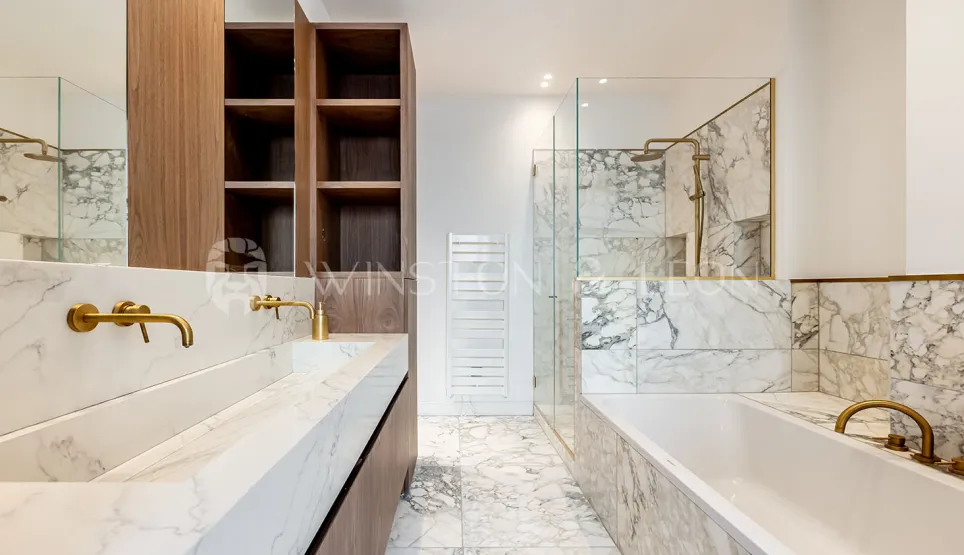 Modern luxury bathroom: white marble, double vanity, gold fixtures, walk-in shower and bathtub. Elegant design.