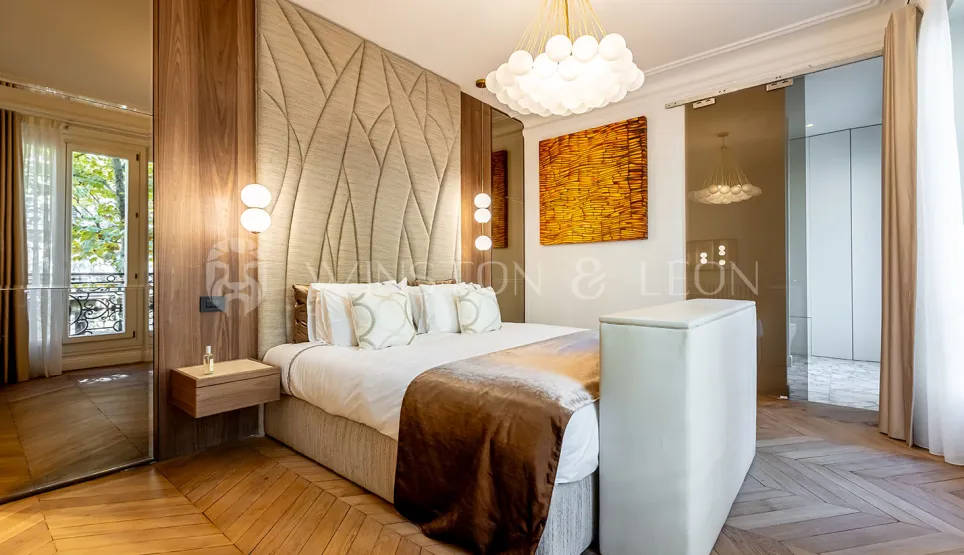 Modern luxury bedroom featuring upholstered headboard, chevron parquet, designer lighting, and artistic accents. Parisian elegance.
