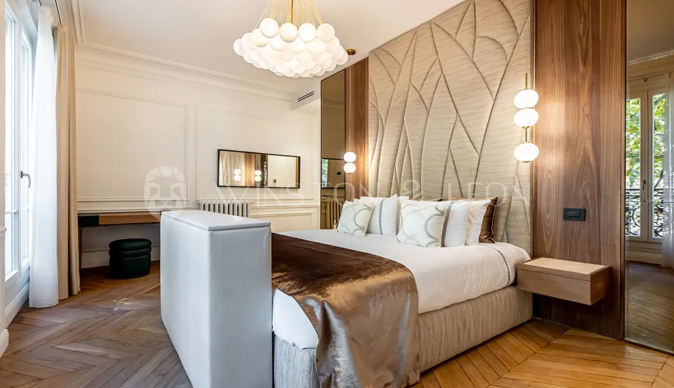 Luxurious bedroom with contemporary and classic design. Textured headboard, elegant parquet, sophisticated lighting. Ideal for high-end real estate.