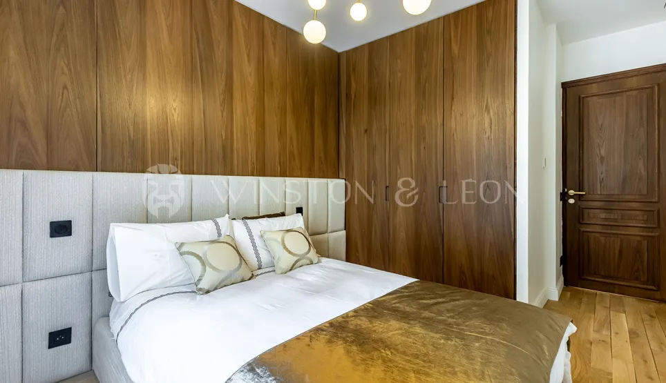 Modern luxury bedroom featuring elegant wood paneling, comfortable bed and padded headboard. Refined design for a master suite.