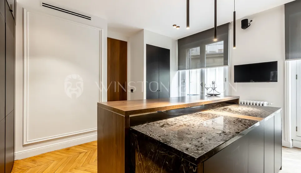 Modern luxury interior: designer kitchen with marble and wood island, pendant lighting, wall TV. Contemporary elegance.