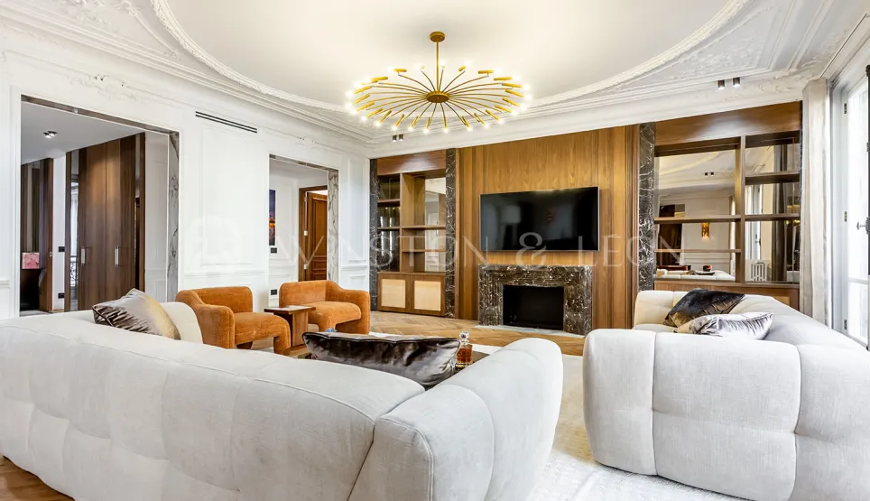 Luxury contemporary living room with marble fireplace, integrated TV, white sofas & gold chandelier. Elegant interior design for prestige apartment.