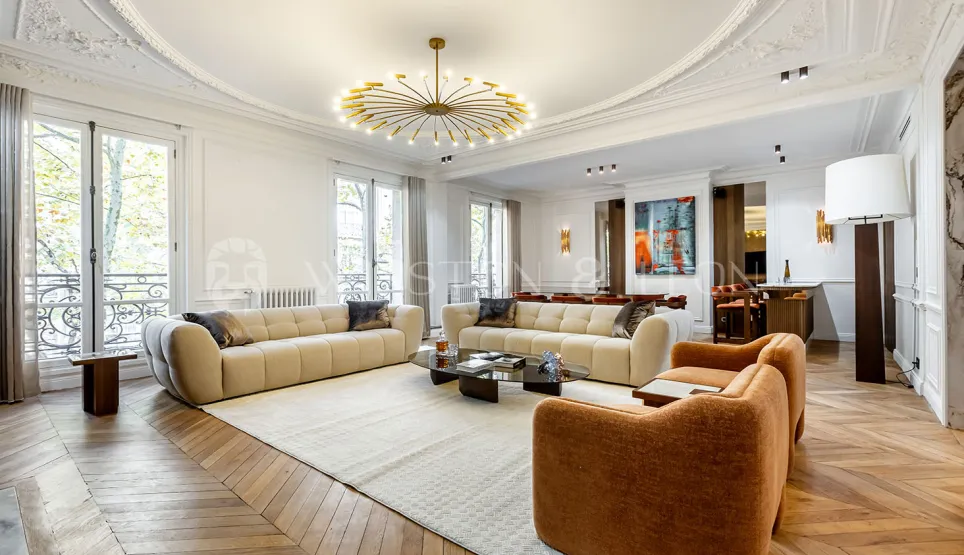 Luxury Haussmannian living room. Contemporary design, herringbone parquet, elegant moldings, and modern chandelier. Prestige apartment.