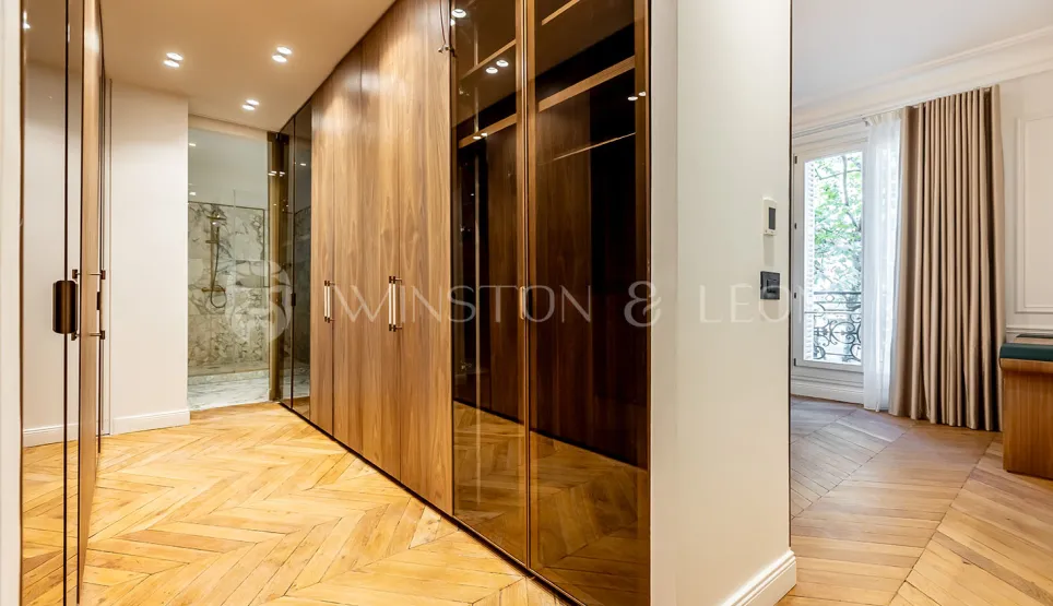 Luxury bespoke dressing room with wood and glass, herringbone parquet. Adjoining bathroom. Elegant design for a prestige apartment.