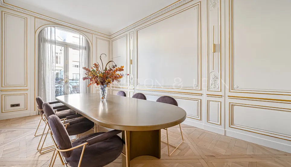 Prestigious Parisian dining room, gold moldings, herringbone parquet, modern furniture. Luxury and refinement.