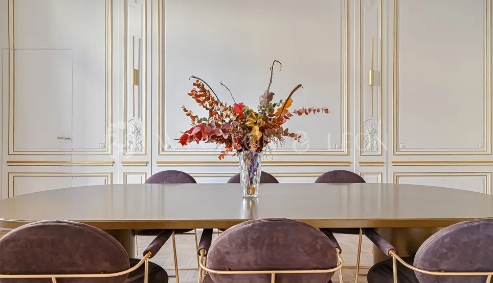 Luxury Haussmannian apartment: elegant dining room. Gold moldings, contemporary velvet chairs & design table. Refined decoration.