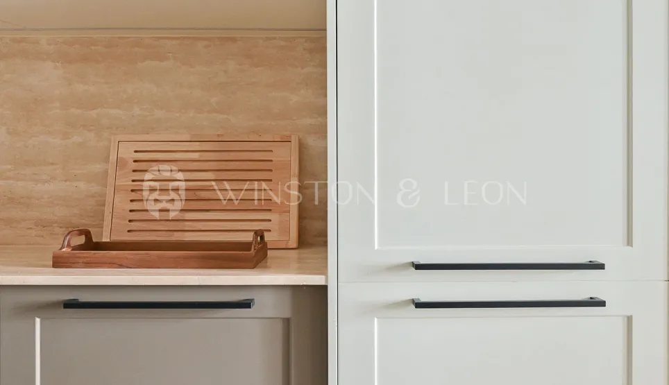 Modern luxury kitchen: light cabinets, black handles, travertine backsplash, wood accents. Elegant and functional design.