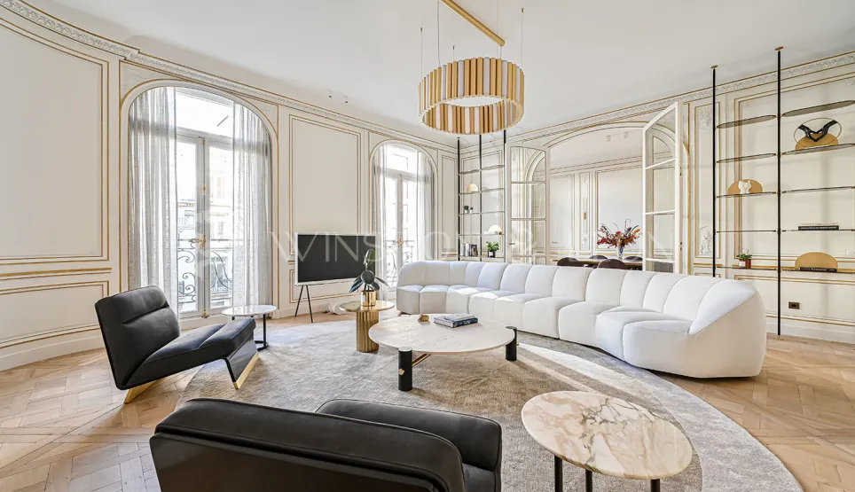 Exceptional Parisian Haussmannian living room: gold moldings, herringbone parquet, white designer sofa, luxury furniture, natural light.
