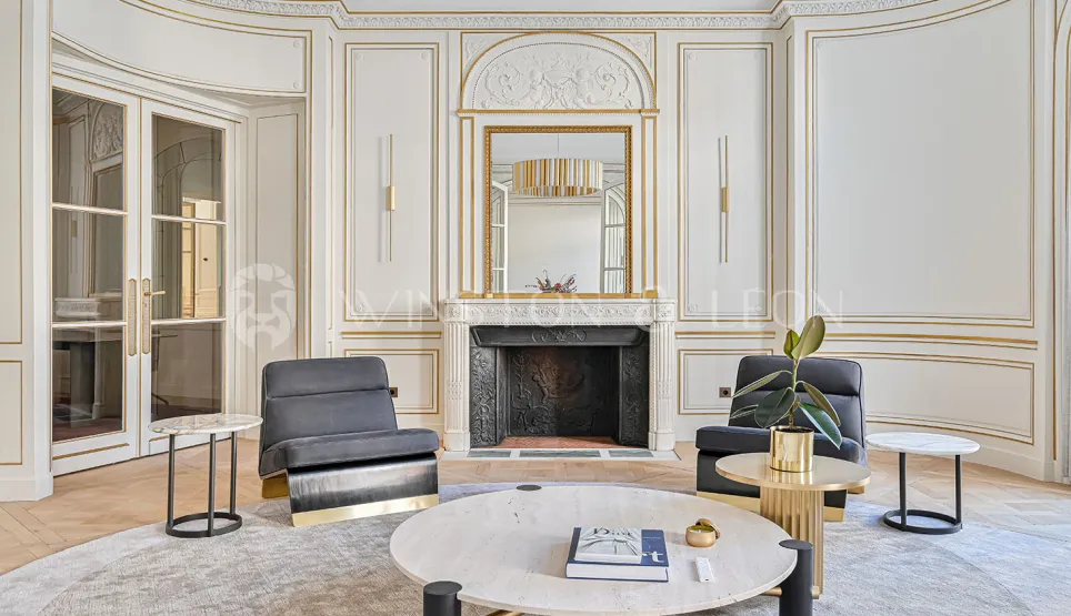 Chic Parisian luxury apartment, Haussmannian living room with gold moldings, marble fireplace & contemporary design furniture.