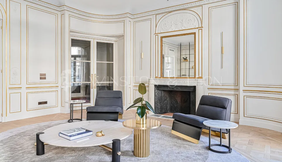 Luxury Parisian Haussmannian living room. Golden moldings, fireplace, contemporary design furniture. Timeless elegance.
