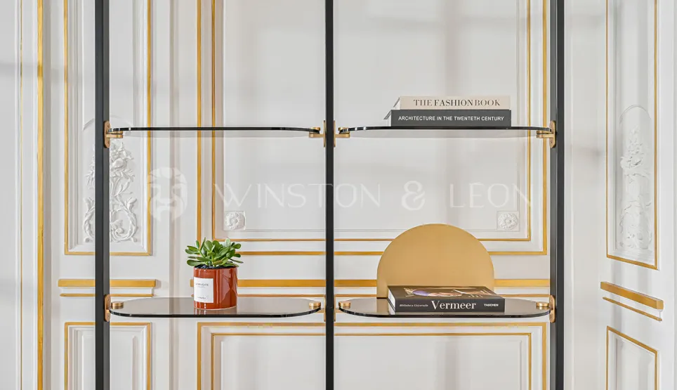Luxury design shelf in glass and black metal, gold accents, against classic Haussmannian wall panels. Contemporary elegance and refinement.