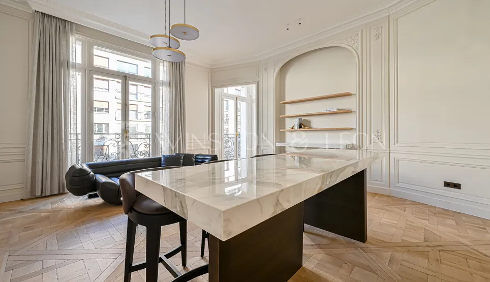 Luxury Parisian apartment with open-plan kitchen, marble island, herringbone parquet, and classic mouldings. Elegant modern design.