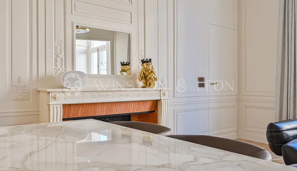 Elegant Haussmannian interior: classic moldings, ornate fireplace, mirror, marble table. Refined Parisian luxury, chic design.