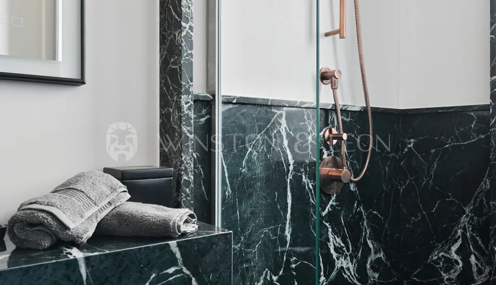 Luxury bathroom with veined green marble and copper fixtures. Elegant shower, contemporary design. Ideal for high-end real estate.