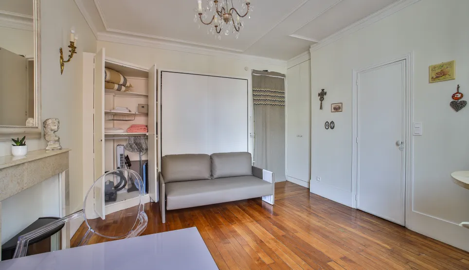 Luxury optimized studio featuring a convertible sofa, hardwood floors, and integrated storage. Parisian elegance & functionality.
