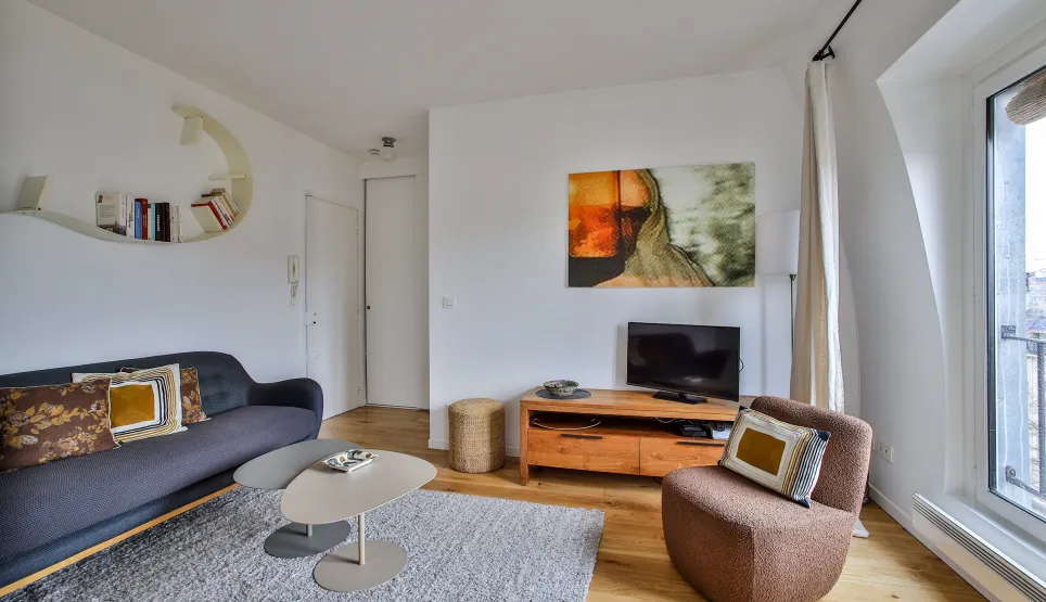 Bright, modern living room featuring designer furniture, contemporary art, and hardwood floors. Refined ambiance for a luxury Parisian apartment.