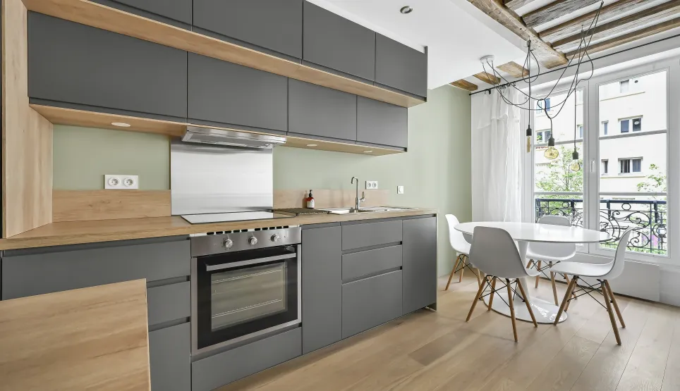 Modern anthracite grey and light wood kitchen. Sleek design, exposed beams, city view. Bright luxury apartment.