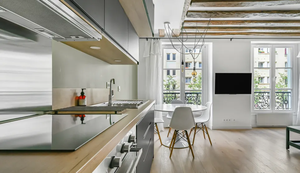 Luxury apartment: modern open kitchen, bright living room, exposed beams, hardwood floors. Parisian elegance.