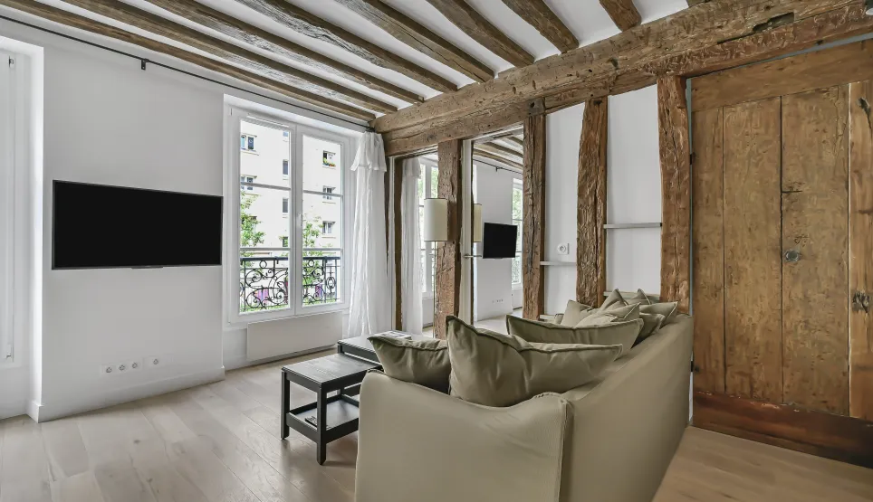 Bright luxury Parisian apartment living room with exposed beams, light wood floor, and modern touches. Charm and elegance.