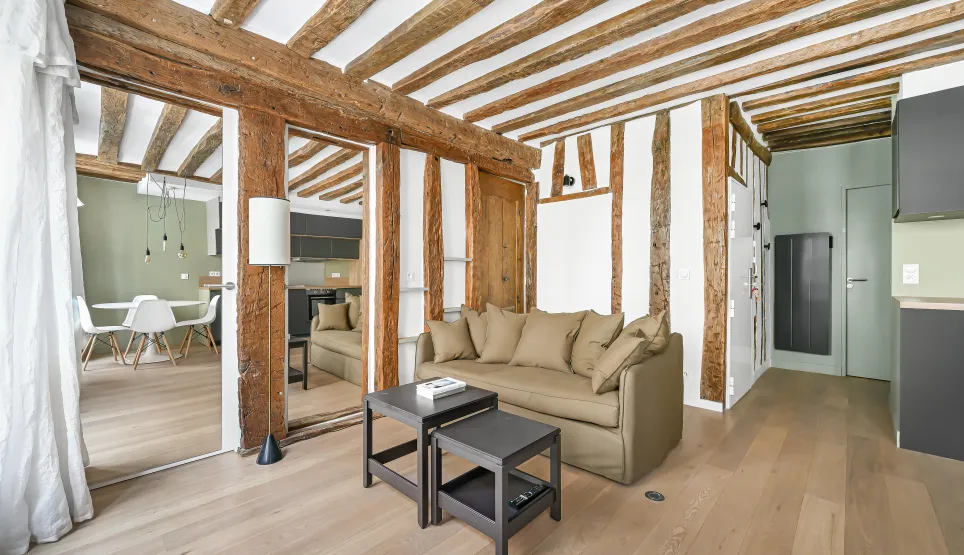 Stunning luxury Parisian apartment. Living room with exposed beams, light wood floor. Contemporary design & renovated historic charm.