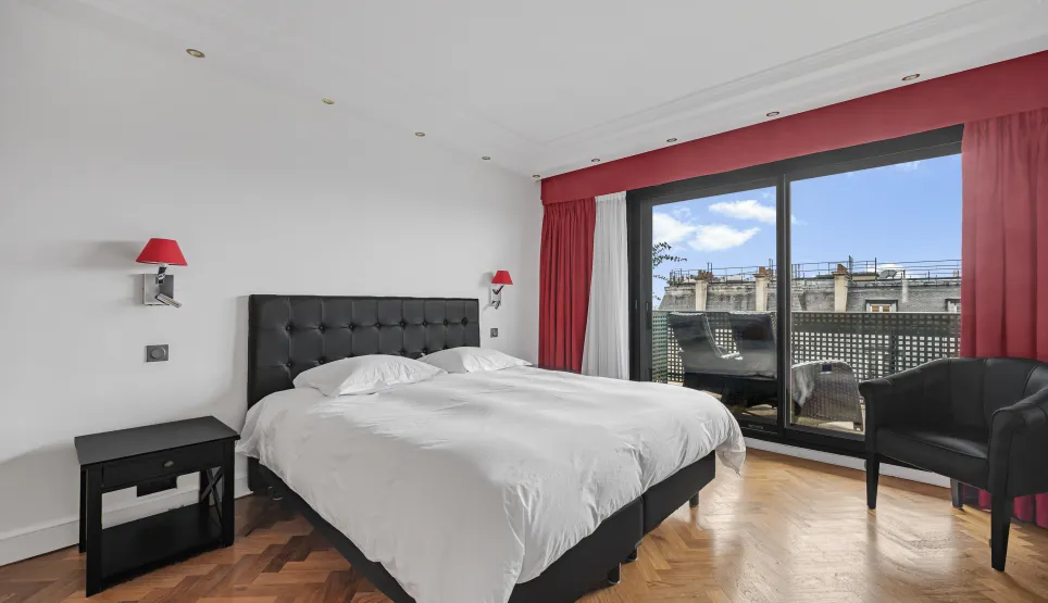 Modern luxury bedroom featuring a king-size bed, parquet floor, private balcony, and city views. Elegant, bright design for optimal comfort.