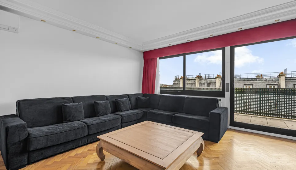 Bright, modern luxury living room. Large sofa, hardwood floor, Paris rooftop view and balcony.