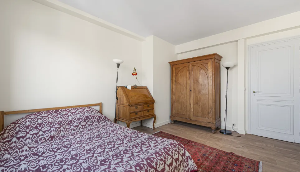 Elegant bedroom with antique solid wood furniture: wardrobe, secretary desk. Comfortable bed, hardwood floor, oriental rug. Timeless charm.