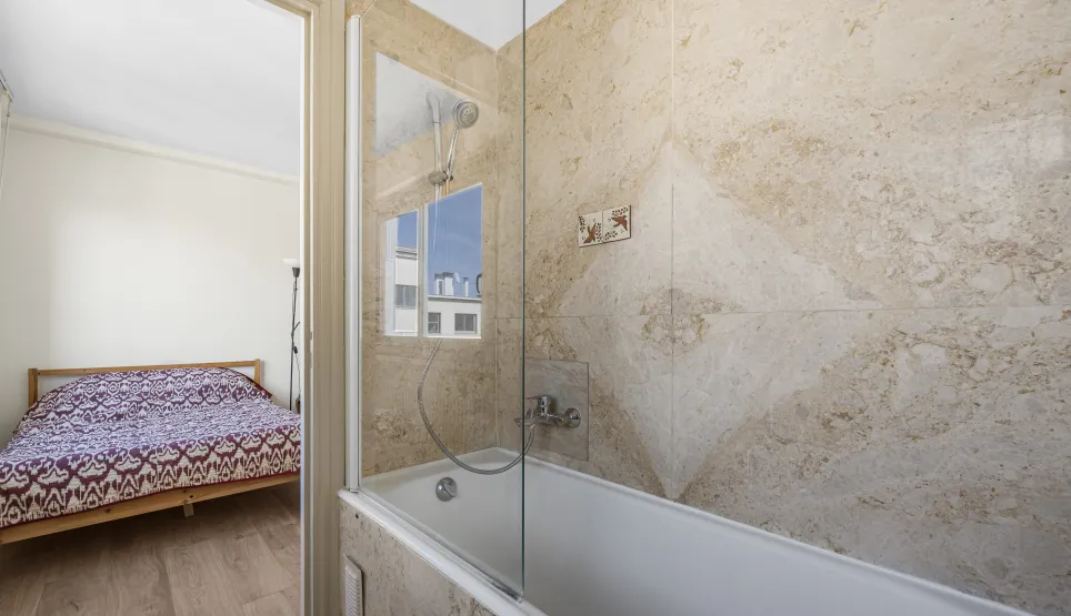 Explore this modern en-suite: bathroom with tub, shower & natural stone walls, opening to a bright bedroom. Functional luxury.