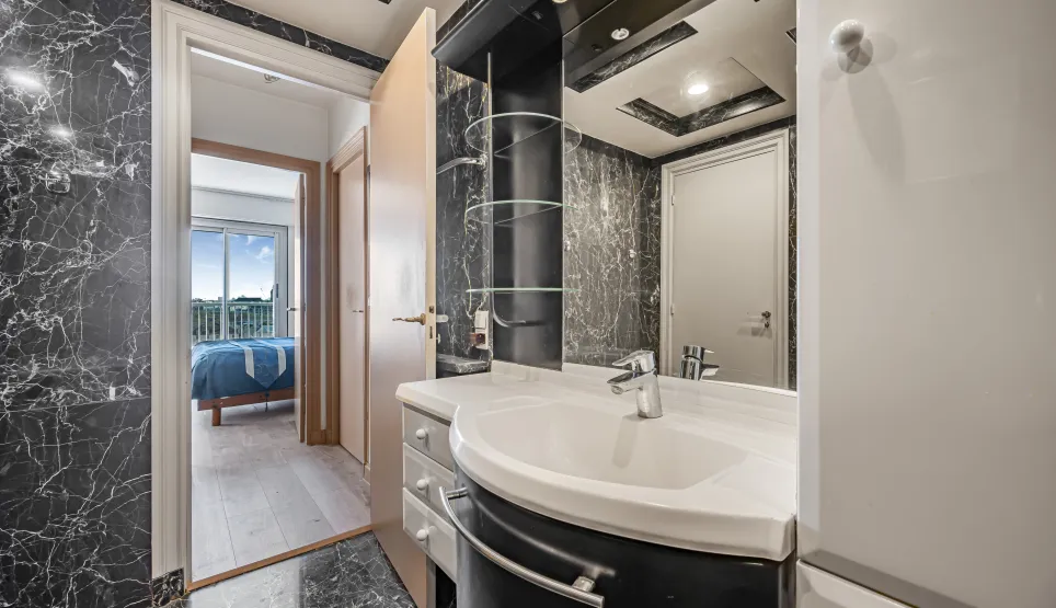 Elegant black marble bathroom, modern design with integrated sink. Access to bright master suite with view. Luxury and comfort.