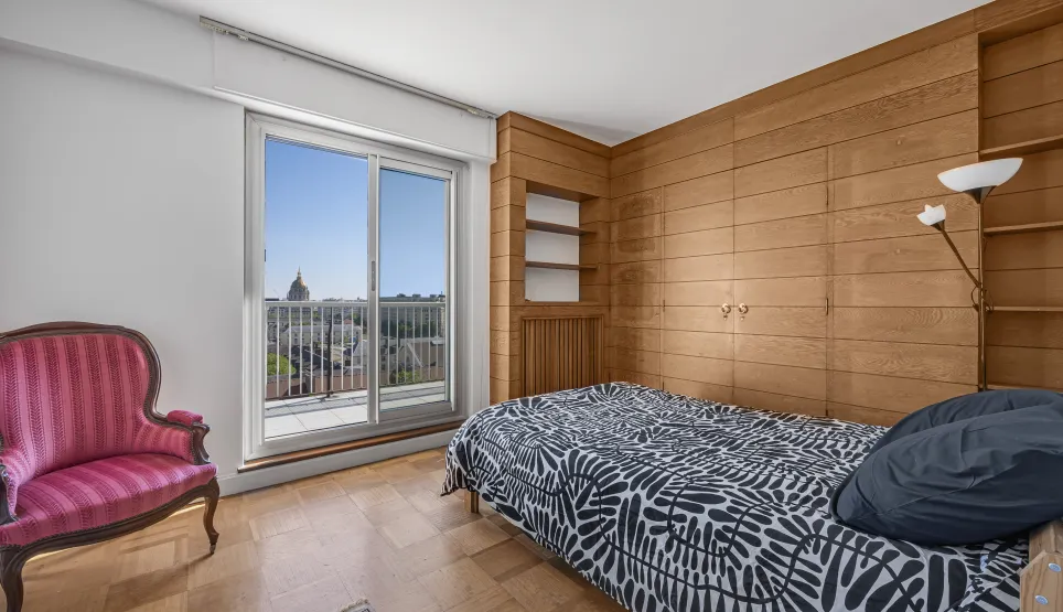 Elegant bedroom with wood paneling, parquet, and balcony offering a breathtaking city dome view. Luxury and serenity at the heart of the apartment.