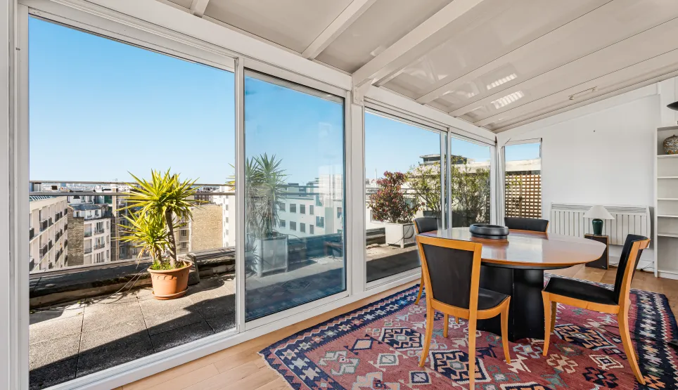 Bright dining room with panoramic city views and terrace access. An elegant and sunny urban living space.
