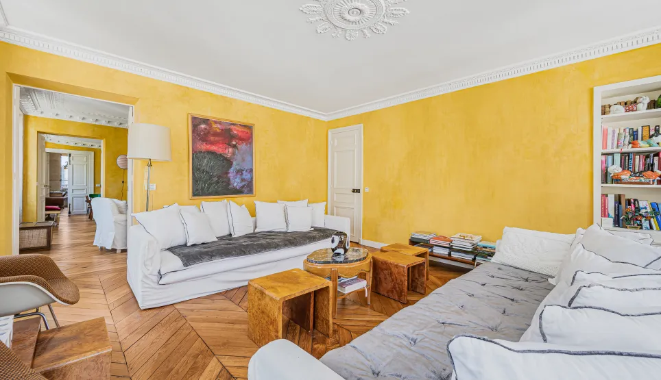 Bright luxury Parisian living room: yellow walls, chevron parquet, moldings, white sofas. Elegance & comfort.