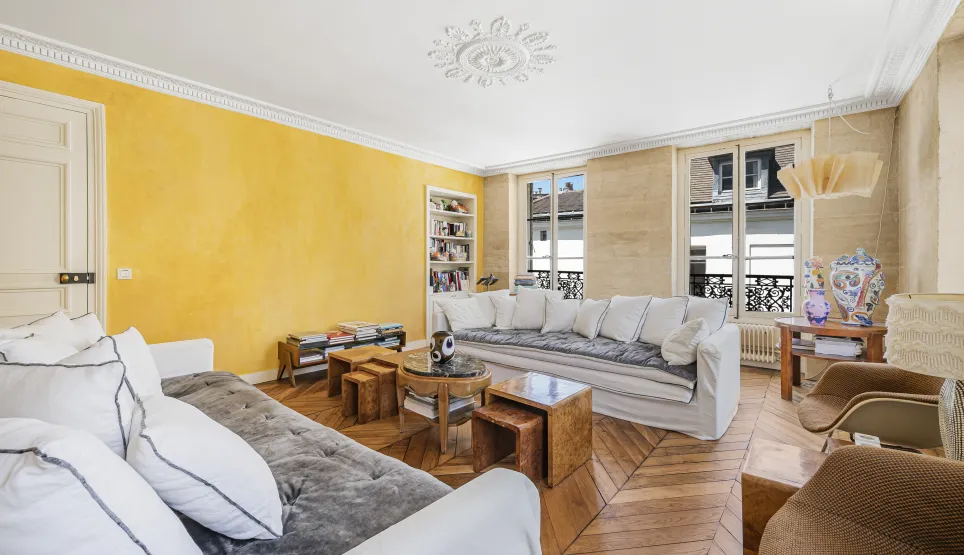 Bright luxury living room with textured yellow wall, parquet, moldings & white sofas. Parisian elegance.