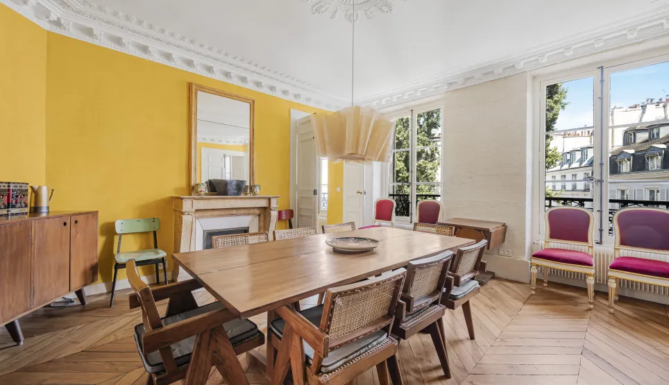 Luxury Parisian apartment: bright dining room with parquet, moldings, fireplace, and city view. Haussmannian elegance.
