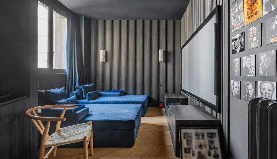 Luxury home cinema: blue velvet seating, large screen, designer walls. Immersive experience for high-end entertainment.