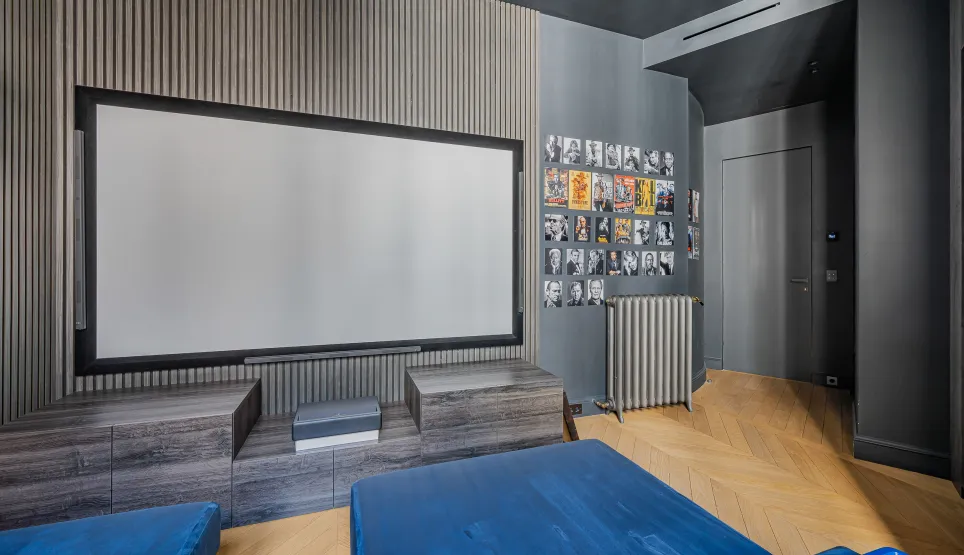 Luxury private home cinema with modern design. Large screen, elegant wood paneling, herringbone floor. Premium immersive experience.